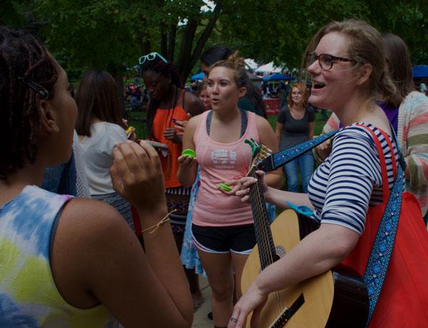 A group of students playing instruments and singing on the quad.